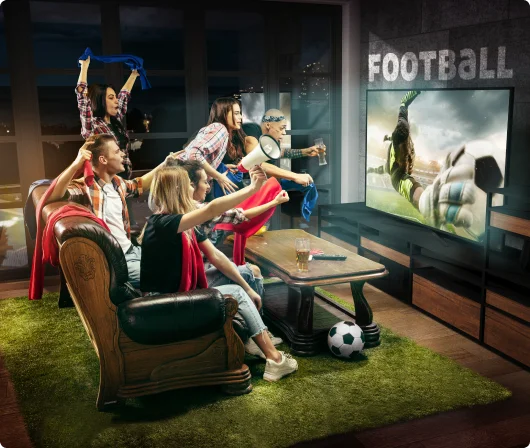 A diverse crowd gathered around a television, engrossed in watching a football match together.